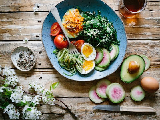Prato equilibrado com vegetais, ovo e abacate sobre mesa de madeira